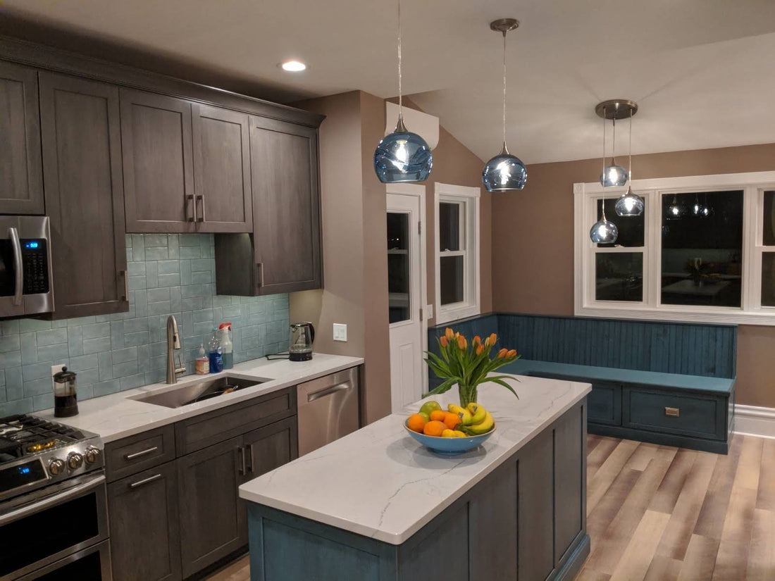 Bicycle Glass Co. swell 767 single pendant lights in steel blue over a gray and blue kitchen island with a 3 pendant cascade chandelier also featuring the swell 767s in steel blue over a breakfast nook