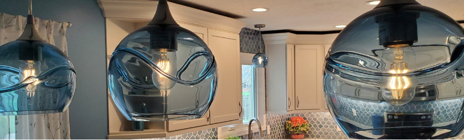 three blue glass globes hanging with a white and blue kitchen in the background