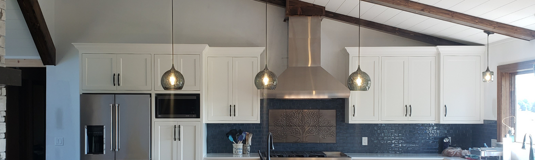 photo of kitchen with tall slanted ceiling featuring three glass pendant lights 