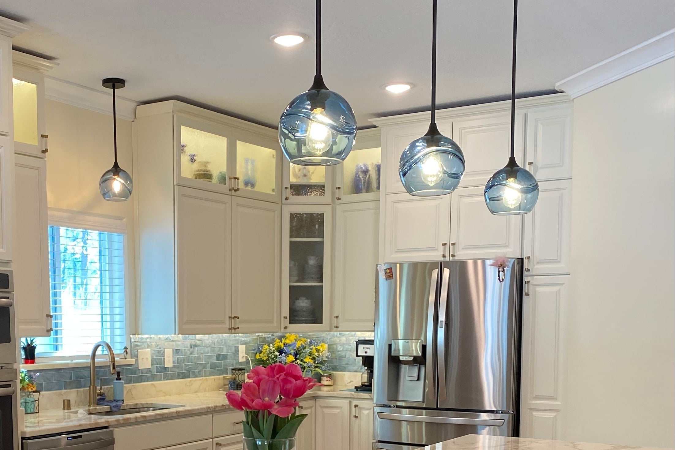 Modern kitchen with white cabinets, marble countertop, and stainless steel appliances.